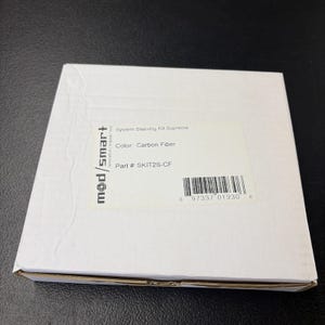May include: A white box with the text "System Sleeving Kit Supreme" and "Color: Carbon Fiber." The box also has a barcode and the text "mod/smart" on the side.
