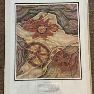 Puede incluir: Una impresión enmarcada de pinturas rupestres Chumash. La obra de arte presenta diseños geométricos rojos y marrones que se asemejan a soles y ruedas sobre un fondo beige y marrón. La impresión incluye el texto "Chumash Cave Paintings".