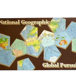 May include: A rectangular National Geographic Global Pursuit board game box featuring a brown background with a stylized, multi-faceted world map graphic in shades of blue, green, and yellow. The text National Geographic and Global Pursuit is printed in a bold, light-colored serif font.