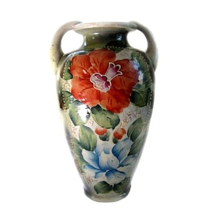 May include: A ceramic vase with two handles featuring a hand-painted design of a large orange-red flower at the top and a smaller blue flower at the bottom, surrounded by green leaves and gold-toned accents on a light gray background.