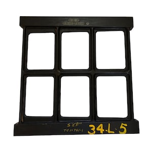 May include: A black metal industrial part with six rectangular openings. The part has the text "SKF TC11761-1" and "34.L.5" in yellow. The top of the part has the text "18-1761-30".