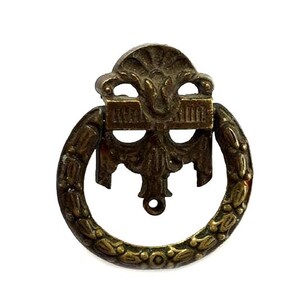 May include: Antique bronze-toned drawer pull with a decorative design. The pull features a circular handle adorned with a leaf pattern and an ornate backplate. The hardware is likely made of metal and is designed for furniture.