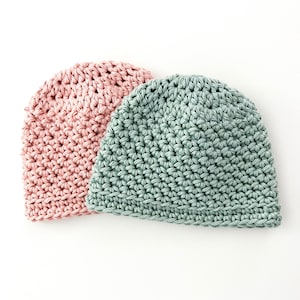 May include: Two crocheted hats, one in a light pink colour and the other in a light green colour.