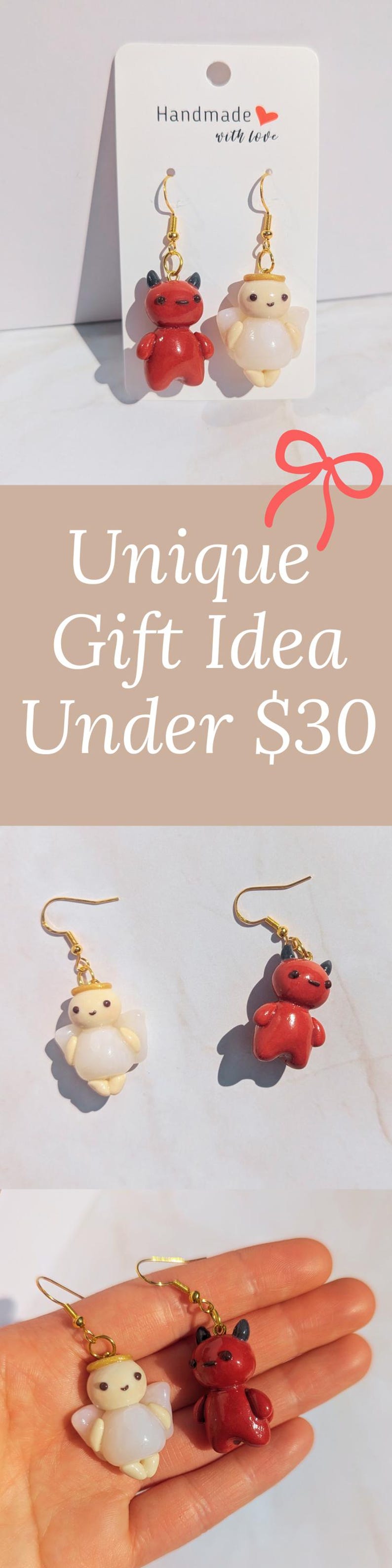 Puede incluir: Pendientes hechos a mano con un diablo rojo y un &aacute;ngel blanco, ambos con ganchos dorados. Los pendientes se muestran en una tarjeta blanca con el texto "Handmade with love".