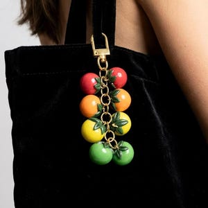 Colorful tomato keychain bag charm crafted from handmade polymer clay cherry tomatoes. Functional key ring for keys, purse charm for handbags, and zipper pull for backpacks and totes. Cute fruit keychain gift for garden lovers, cottagecore aesthetics, and maximalist fashion fans.