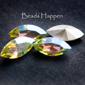 May include: Three marquise-cut crystals with an iridescent yellow and pink finish and one opaque white marquise-cut crystal. The text Beads Happen is displayed above the crystals. These faceted stones feature pointed ends and a reflective surface.