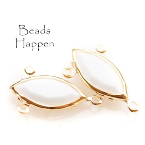 May include: Two gold-toned metal connector pieces with white oval-shaped inserts. Each piece has three loops for attaching jewellery.
