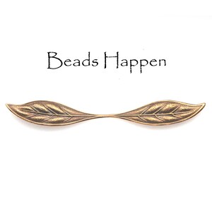May include: A pair of gold-toned metal leaf-shaped bead caps. The caps are designed to be used as a connector for jewelry making.