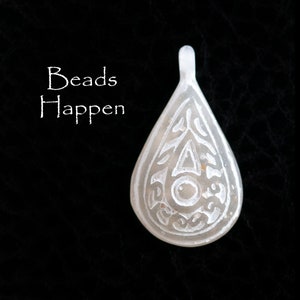 May include: White glass teardrop pendant with an intricate etched design. The pendant has a hole at the top for stringing. The text "Beads Happen" is written in white on a black background.
