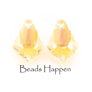 Op de afbeelding: Twee gele kristallen kralen met een facetgeslepen ontwerp. De kralen liggen op een witte achtergrond. Beads Happen staat onder de kralen.