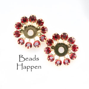 Könnte beinhalten: Zwei goldfarbene Metallperlenkappen mit einem Kreis aus roten Strasssteinen am Rand. Der Text "Beads Happen" ist unter den Perlenkappen gedruckt.