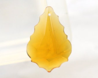May include: A teardrop-shaped amber crystal prism with a faceted design. The prism is made of glass and has a smooth, shiny finish.