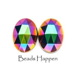May include: Two iridescent oval-shaped glass beads with a faceted design. The beads have a rainbow of colors, including pink, purple, green, blue, and orange.