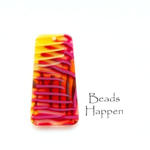 Puede incluir: Una cuenta de vidrio rectangular con un patrón de rayas amarillas, naranjas y rosas. La cuenta tiene un agujero en la parte superior para enhebrar. El texto "Beads Happen" es visible en la imagen.