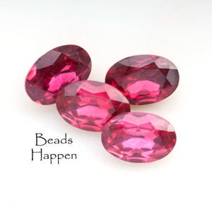 Może przedstawiać: Cztery owalne, różowe koraliki szklane. Koraliki są fasetowane i mają błyszczące wykończenie.