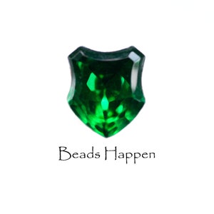 May include: A dark green, faceted, shield-shaped glass bead with the text "Beads Happen" below it.