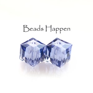 May include: Two clear, faceted, cube-shaped beads in a light blue color. The beads are arranged side-by-side, with the text "Beads Happen" above them.