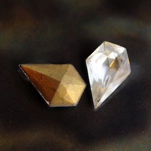 May include: Two faceted glass gems, one clear and one with a gold and brown metallic finish.