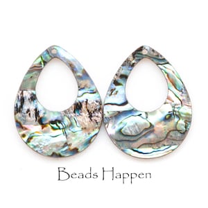 May include: Two iridescent abalone shell teardrop shaped pendants with a hole at the top for stringing. The pendants have a natural, organic pattern and a blue, green, and silver color scheme.