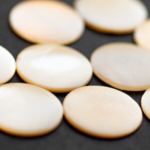 May include: A group of eight round, white, mother-of-pearl buttons.