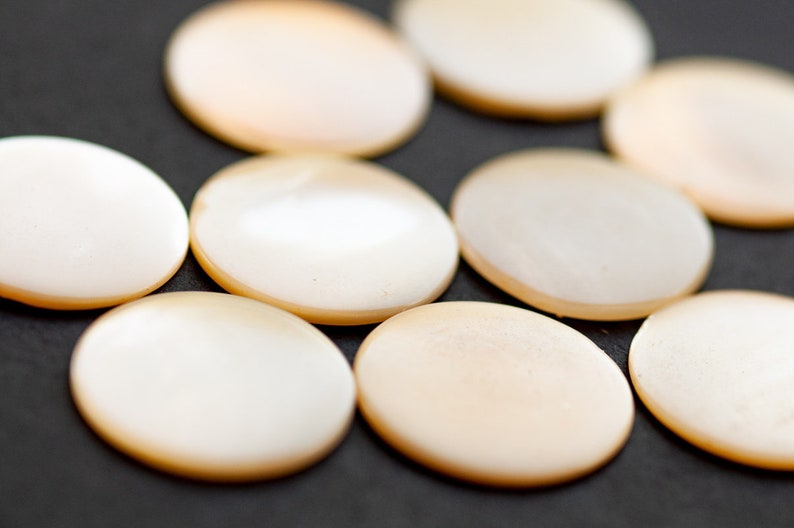 May include: A group of eight round, white, mother-of-pearl buttons.