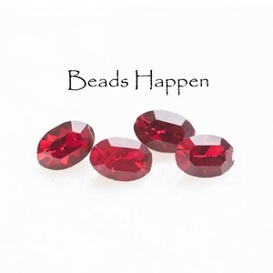 May include: Four oval-shaped, faceted red gemstones are displayed against a white background. The gemstones are a deep, rich red color and have a polished, reflective surface. The text "Beads Happen" is above the gemstones.