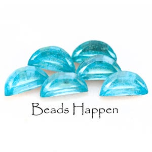 Op de afbeelding: Een groep van zes turquoise blauwe edelsteen kralen, elk in de vorm van een halve cirkel. De kralen zijn in een halve cirkel op een wit oppervlak gerangschikt. De tekst "Beads Happen" is onder de kralen gedrukt.