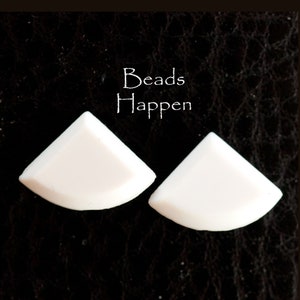 Puede incluir: Dos cuentas blancas de cerámica de forma triangular con bordes redondeados. Las cuentas están sobre un fondo negro. El texto "Beads Happen" está escrito en blanco sobre las cuentas.