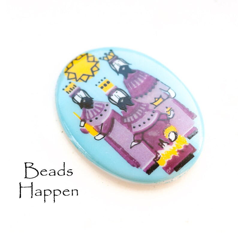 May include: A blue oval ceramic tile with a depiction of the three wise men, each wearing a crown and purple robes, with a yellow star above them. The tile has a white border.