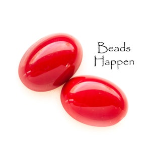May include: Two bright red oval beads, with the text "Beads Happen" written in black above them.