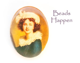 May include: An oval pendant with a vintage portrait of a woman in a white hat and ruffled collar, set against a warm, golden background. The text "Beads Happen" is written in a cursive font to the right of the pendant.