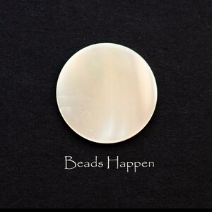 May include: A white, round, smooth, iridescent, mother of pearl bead.