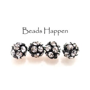 May include: Four black and silver round beads with rhinestones. Beads Happen.