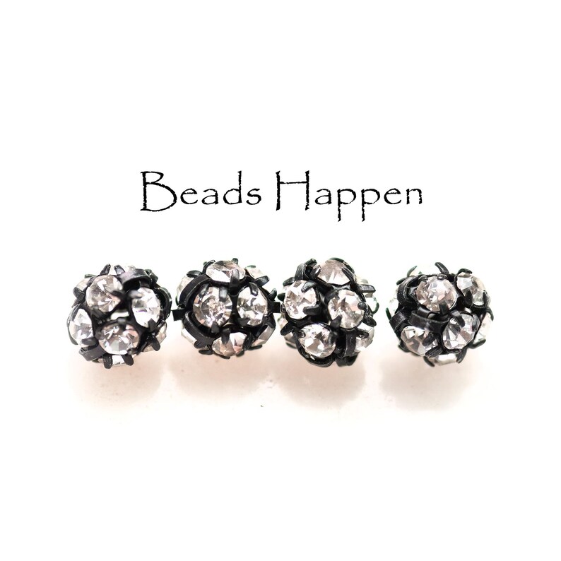 May include: Four black and silver round beads with rhinestones. Beads Happen.