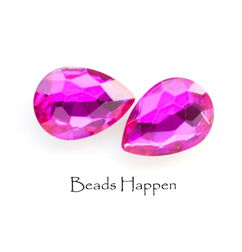 Puede incluir: Dos cuentas de cristal de forma de l&aacute;grima rosa con superficies facetadas. Las cuentas est&aacute;n sobre un fondo blanco. Beads Happen est&aacute; escrito debajo de las cuentas.