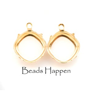 May include: Two gold-colored, square-shaped pendant trays with a loop at the top for hanging. The trays have a decorative edge and a white interior. The text "Beads Happen" is printed below the pendants.