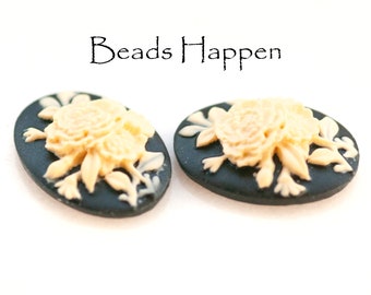 May include: Two black oval-shaped cameos with a raised white floral design. The cameos are approximately 1 inch in diameter.