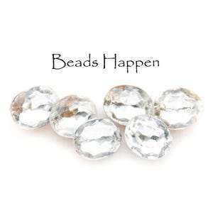 May include: Six clear glass oval beads with a faceted design. The beads are arranged in a row on a white background. The text "Beads Happen" is written above the beads.