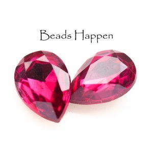 May include: Two teardrop-shaped, faceted, pink glass beads.