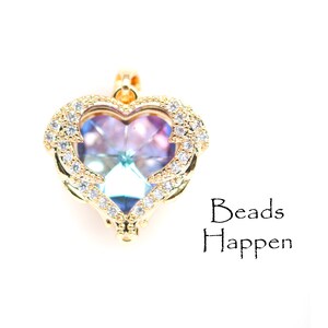 May include: A gold heart-shaped pendant with a clear iridescent crystal in the centre. The pendant is surrounded by a halo of small clear crystals.