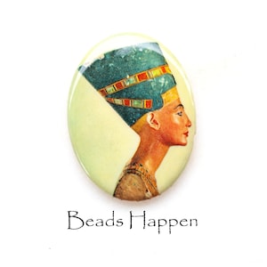 May include: Oval-shaped ceramic tile with a colorful image of an Egyptian queen wearing a blue and gold headdress. The tile has a light green background and the text "Beads Happen" is printed below the image.