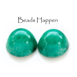 May include: Two round, green, cabochon beads with a white marbled pattern. The beads are smooth and glossy.