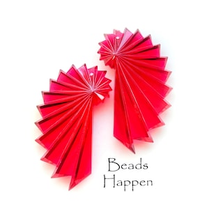 May include: Two bright red acrylic fan-shaped beads. The beads are made of clear acrylic and have a spiral design. The beads are about 2 inches in diameter. The text "Beads Happen" is printed in black below the beads.