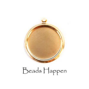 Puede incluir: Un colgante redondo de color dorado con un lazo en la parte superior para sujetarlo a una cadena. La bandeja tiene un área empotrada plana para sostener un diseño. El texto "Beads Happen" está impreso en escritura negra debajo.