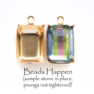 May include: Two gold-coloured rectangular pendant settings with prongs, one empty and one with a multi-coloured, iridescent rectangular stone. The text "Beads Happen" is below the pendants, with a note about the sample stone and prongs.