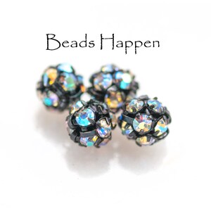 May include: Four iridescent black and silver round beads with rhinestones. Beads Happen.
