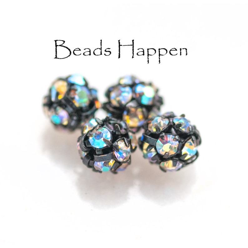May include: Four iridescent black and silver round beads with rhinestones. Beads Happen.