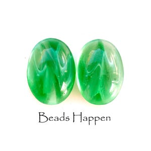 Op de afbeelding: Twee groene, ovale glazen kralen met witte swirls. De kralen zijn doorschijnend en hebben een glanzende afwerking.