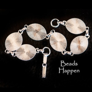 May include: Silver chain bracelet with round, textured links. The bracelet has a clasp closure and the text "Beads Happen" is visible in the image.