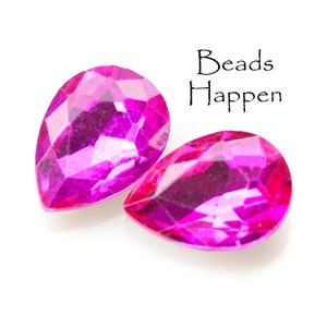 Puede incluir: Dos cuentas de color rosa nacarado en forma de l&aacute;grima sobre un fondo blanco. El texto "Beads Happen" est&aacute; escrito encima de las cuentas.